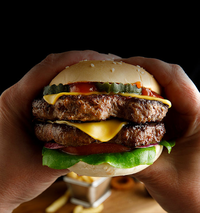 double hamburger held by hands