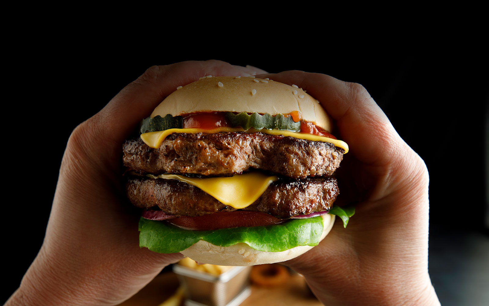 double hamburger held by hands
